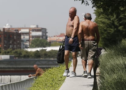 De las 50 provincias, 23 se encuentran en alerta por calor sofocante. La gran mayoría de los avisos de la Meteorología son amarillos, es decir, el primer nivel de una escala de tres. En la imagen, unos hombres pasean por un parque de Madrid sin camiseta.