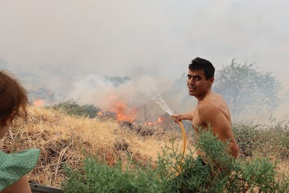 Un vecino trataba de extinguir las llamas el sábado con una manguera. 