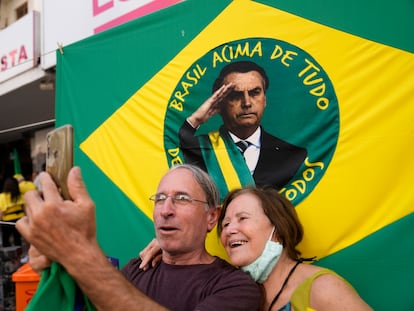 Dos seguidores de Jair Bolsonaro se fotografían frente a una bandera con la imagen del entonces presidente, el 16 de agosto de 2022.