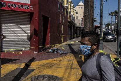 El cuerpo de una mujer no identificada yace sobre la acera de una calle en pleno centro de Tijuana. El cadáver permaneció más de 12 horas en el lugar sin ser removido por las autoridades, debido a la sobrecarga de trabajo de los servicios forenses en la entidad.
