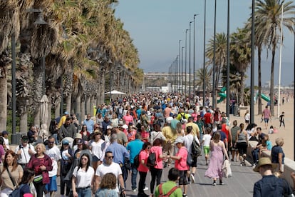 Cientos de personas pasean el domingo por el paseo marítimo de la playa de la Malvarrosa, en Valencia, en un día en que las temperaturas ya rondaron los 30 grados.