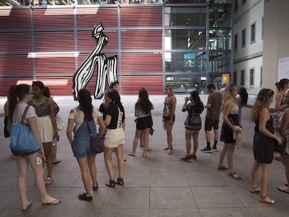 Un grupo de jóvenes turistas esperan para comprar su entrada del Museo Reina Sofía junto a la escultura 'Brushstroke' de Roy Lichtenstein.