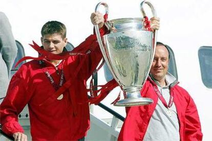 Rafa Benítez aúpa la copa junto a Gerrard al bajar del avión.