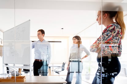 Grossi writes on a whiteboard in front of two employees of his company, iLovePDF, at its headquarters in Barcelona.