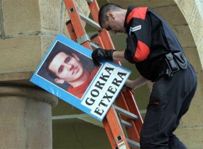 Un <i>ertzaina</i> retira la foto de un preso de ETA en Arrigorriaga, Vizcaya, el 20 de junio.