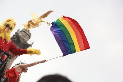 Un manifestante iza la bandera arcoiris bajo el monumento del Ángel de la Independencia