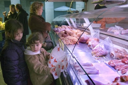 Dos niñas ante el puesto de una pollería en el mercado de La Boquería, en Barcelona.