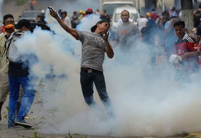 Un manifestante se enfrenta a la policía lanzando un bote de gas lacrimógeno durante las protestas contra el Gobierno venezolano en Caracas.