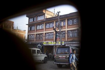 "Riesgos asumibles por cuerpos de cristal que no temen fragmentarse y a los que no les importa no perdurar en el tiempo". Un hombre camina junto a una carretera de Katmandú (Nepal); al fondo, dos hombres subidos en una escalera tratan de arreglar una maraña de cables del tendido eléctrico.