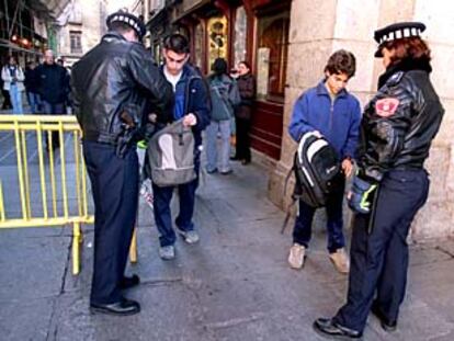 Una pareja de policías municipales registra las mochilas de dos jóvenes que entraban a la plaza Mayor desde la calle de la Sal.