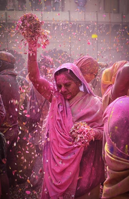 Una mujer viuda india cubierta de polvos de colores mientras sostiene pétalos de flores en el festival Holi en Vrindavan (India), el 27 de febrero de 2018.
