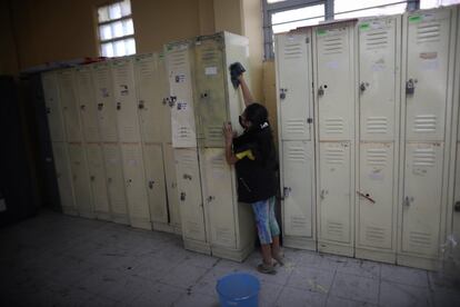 Los padres de alumnos también se han sumado a la tarea de alistar las escuelas para el regreso a clases. En la imagen, una madre limpia los casilleros en un pasillo de la escuela.