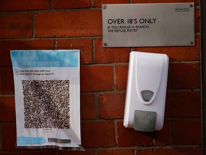 Un código QR para la app del sistema de salud británico en la entrada de un bar en Manchester (Reino Unido) junto a un dispensador de gel.