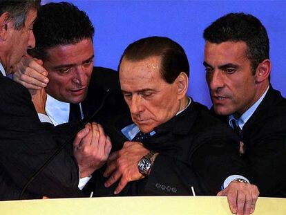 Tres colaboradores sostienen a Silvio Berlusconi en el momento en el que sufre el desmayo.