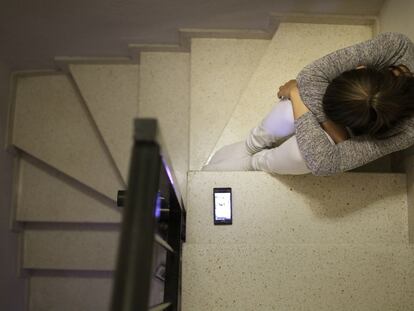 Una adolescente junto a su teléfono móvil.