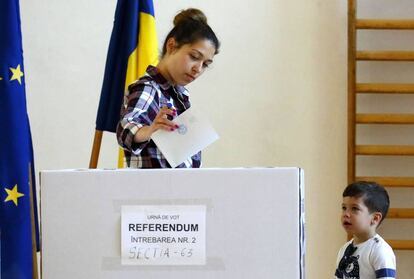Un niño mira como su madre ejerce su derecho al voto en Bucarest (Rumania).