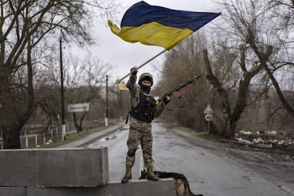 Un soldado ondea una bandera de Ucrania en un puesto de control en Bucha, a las afueras de Kiev. Rusia anunció que sus fuerzas destruyeron 14 objetivos militares ucranios, entre ellos dos puestos de mando, dos lanzaderas de misiles antiaéreos, dos arsenales de artillería, tres depósitos de combustible y seis fortificaciones.