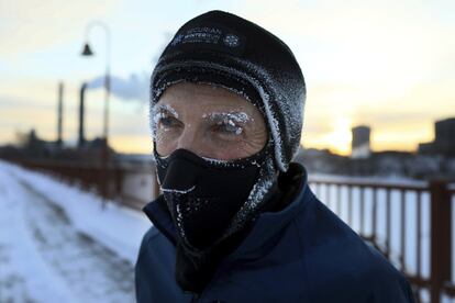 Um homem com o rosto coberto de geada enquanto atravessa o Stone Arch, que atravessa o rio Mississippi, em Minneapolis.