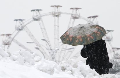 Una mujer pasea por un nevado Kiev, con una noria de fondo.