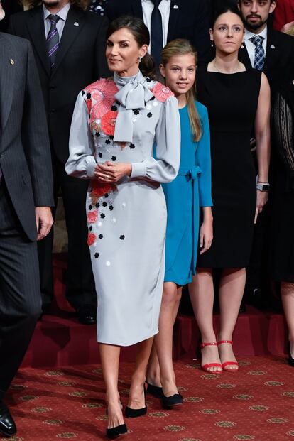 El diseñador Jorge Vázquez ha tomado las riendas de Pertegaz y una de las primeras en lucir un diseño de esta nueva etapa de la firma ha sido la reina, que ya confió en esta marca para el día de su boda. En el encuentro con los galardonados en los premios Princesa de Asturias, la madre de Leonor apostó por un vestido gris de manga larga a media pierna, con flores rosas bordadas y lazada al cuello.