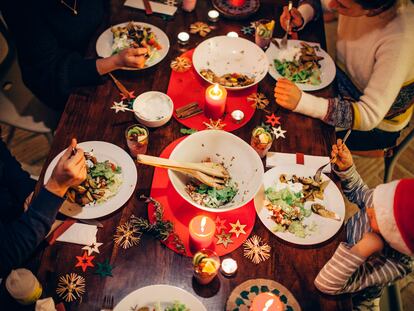 Una familia come alrededor de una mesa decorada con motivos navideños.