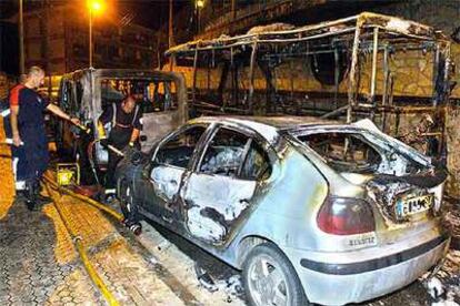 Los bomberos trabajan junto a uno de los vehículos incendiados el sábado en San Sebastián.