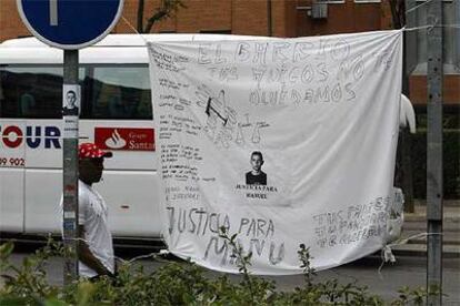 Un inmigrante pasa ante una sábana con pintadas alusivas a la muerte de Manu, en la calle de Villafuerte.
