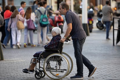 Un hombre desplaza en silla de ruedas a una mujer mayor el pasado mes de octubre en Sevilla.