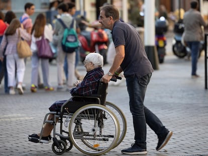 Un hombre desplaza en silla de ruedas a una mujer mayor el pasado mes de octubre en Sevilla.