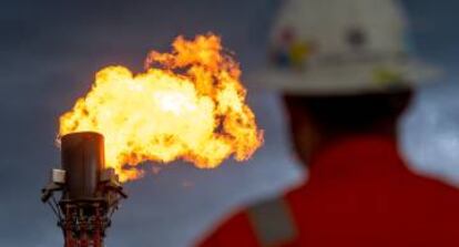 Un operario observa la quema de gas en una plataforma de extracción.