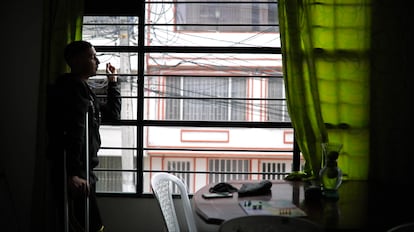Diego Barceló fuma un cigarrillo desde la ventada de su casa en Bogotá.