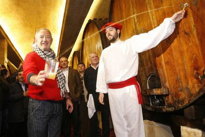 Un <i>dantzari</i> escancia la sidra de una barrica en el vaso del cocinero Karlos Arguiñano, ayer en Astigarraga.