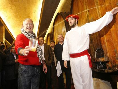 Un <i>dantzari</i> escancia la sidra de una barrica en el vaso del cocinero Karlos Arguiñano, ayer en Astigarraga.