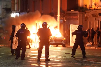 A car burns as Irish policemen stand at the scene of an attack in Dublin city centre, Thursday Nov. 23, 2023