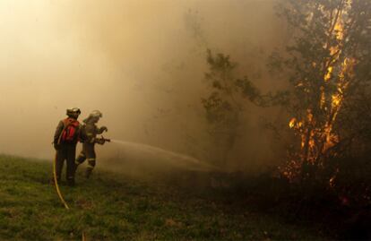 Los bomberos, durante las labores de extinción de un incendio en el pueblo de AS Paradellas (Ourense).