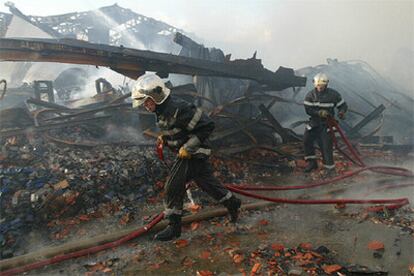 Los bomberos apagan los rescoldos de un incendio en un almacén de textiles chino en Le Bourget, al noreste de País.