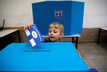 Una niña introduce en una urna el voto de su padre en un colegio en Tel Aviv.