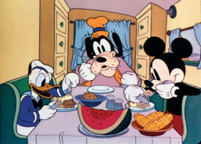 Donald, sentado a la mesa junto a Pluto y Mickey Mouse.