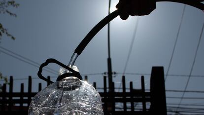 Una persona llena de agua una botella de plástico.