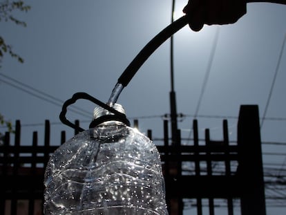 Una persona llena de agua una botella de plástico.