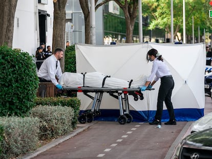 Dos trabajadores de la funeraria levantan el cadáver del hombre asesinado este lunes en una discoteca en Fuenlabrada (Madrid).