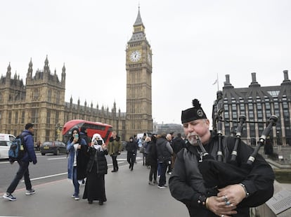 Un hombre toca la gaita en el puente de Westminster junto al Parlamento.