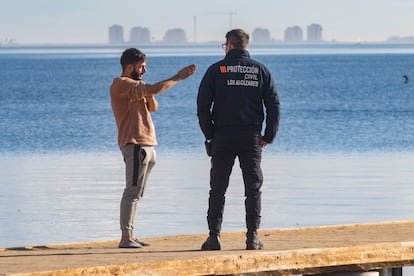 Uno de los dos jóvenes rescatados en Los Alcázares, este viernes, indica a un voluntario de protección civil dónde buscar a su compañero de 15 años desaparecido en aguas del Mar Menor.