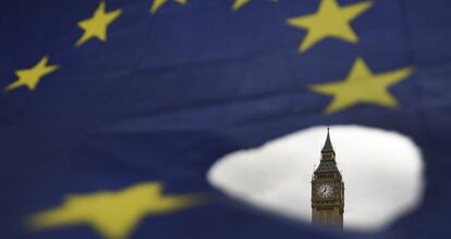 El Big Ben asoma por un roto en una bandera de la Uni&oacute;n Europea en Londres.