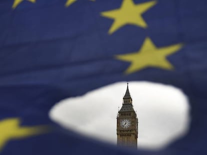 El Big Ben asoma por un roto en una bandera de la Uni&oacute;n Europea en Londres.