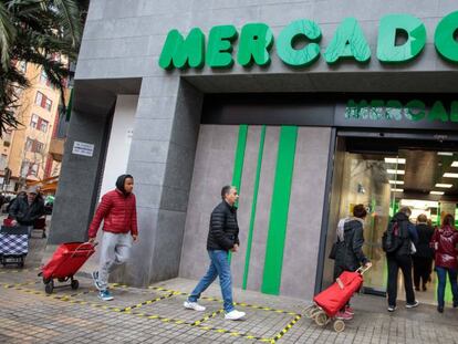 Personas hacen cola en la entrada de un Mercadona respetando la distancia de seguridad marcada en el suelo por la pandemia de coronavirus.