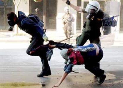 Un policía carga contra dos manifestantes en las calles de Salónica.