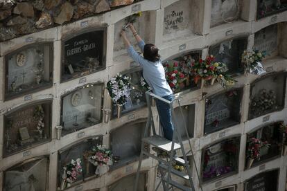Una mujer coloca unas flores en un nicho del cementerio de Montjuïc de Barcelona.