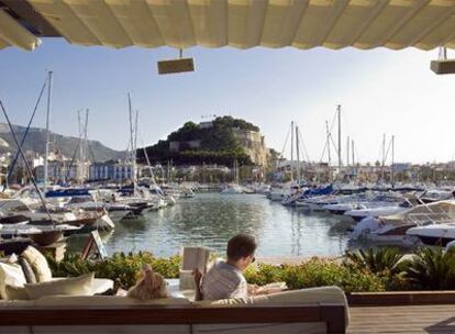 Una pareja lee en la terraza de Zensa, con el castillo de Dénia al fondo.