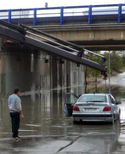 Un vehículo atrapado bajo el puente de la calle Berrocal hacía la avenida de los Rosales, socorrido por un camión grúa.